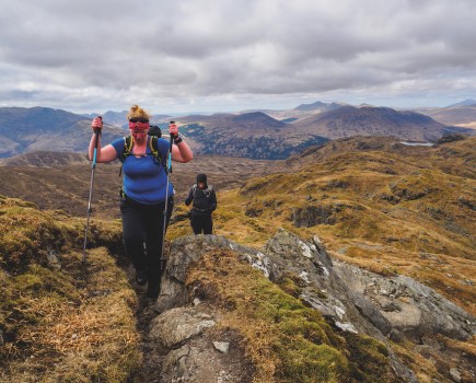 Woman in a black and white jacket looking down at the ground in Glen Coe